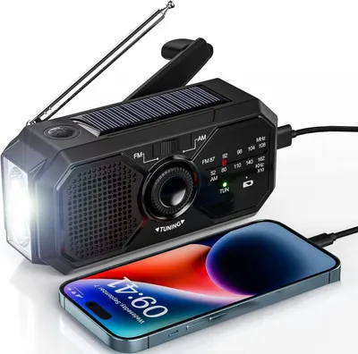 A black emergency radio with a solar panel and flashlight is shown charging a smartphone.