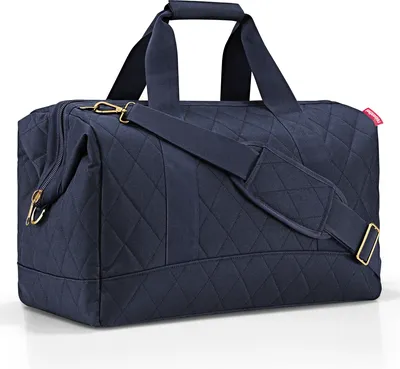 A navy blue quilted duffel bag with gold hardware and a detachable shoulder strap is shown against a white background.