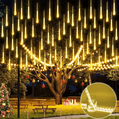 Outdoor scene at night with a decorated tree and Christmas tree.
