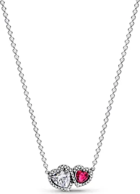 A silver necklace with two heart-shaped pendants, one clear and one pink, set against a white background.
