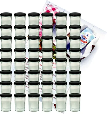 A large set of glass jars with black lids, arranged in stacks, with a recipe booklet in the background.