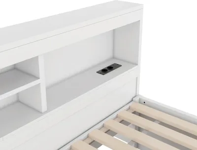 A close-up view of a white bed frame with built-in shelving and a power outlet.