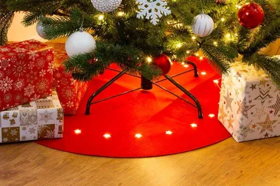 A Christmas tree skirt with lights and presents underneath.