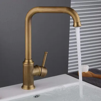 A close-up shot of a bronze-colored kitchen faucet with water running into a white sink.