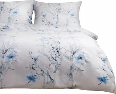 A close-up view of a white duvet cover and pillowcases with a blue floral and branch pattern.