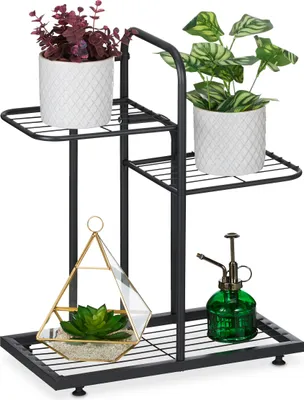 A black metal plant stand with three tiers, holding various plants and decorative items.