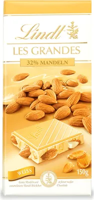 A bar of Lindt Les Grandes 32% Mandeln white chocolate with almonds scattered around it.