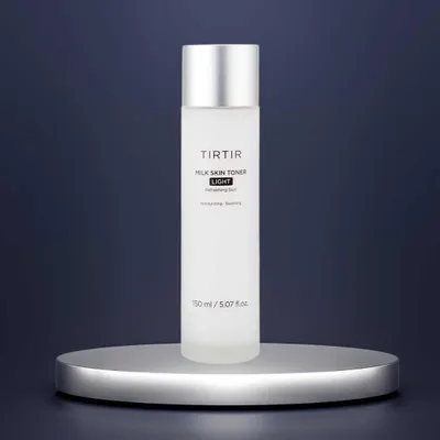 A bottle of Tirtir Milk Skin Toner Light is displayed on a silver pedestal against a dark blue background.