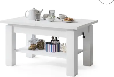 A white coffee table with items on and under it.