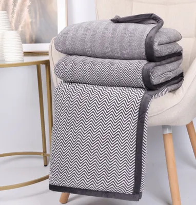 Three folded blankets are stacked on a chair next to a small side table.