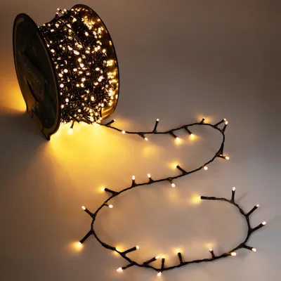 A spool of fairy lights with the lights unspooled and laid out on a surface.