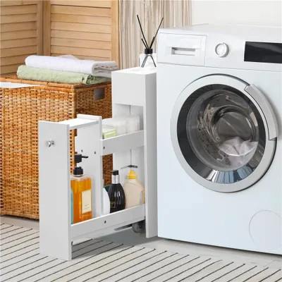 A narrow white cabinet with shelves filled with toiletries is placed next to a white washing machine in a laundry room.