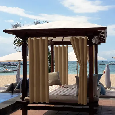 A cabana with curtains on a beach next to a pool.