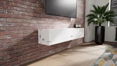 A white floating media console mounted on a brick wall, with a television above it and a potted plant in the background.