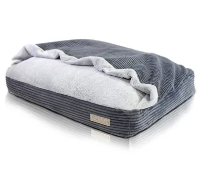 A dog bed with a blanket draped over it, set against a white background.