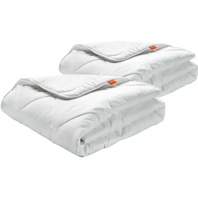 Two white comforters are folded and stacked on a white background.