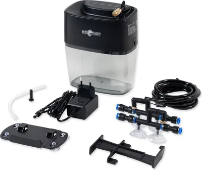 A collection of components for a reptile misting system, including the main unit, power adapter, tubing, and connectors, laid out on a white background.