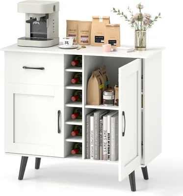 A white sideboard buffet cabinet with a coffee maker, coffee bags, and a vase of flowers on top. The cabinet has a wine rack, a drawer, and two doors.