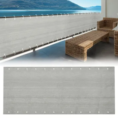 A balcony with a grey privacy screen, wicker furniture, and a view of a lake and mountains.