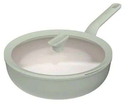 A single green wok pan with a glass lid and a light-colored interior, shown from a diagonal angle against a white background.