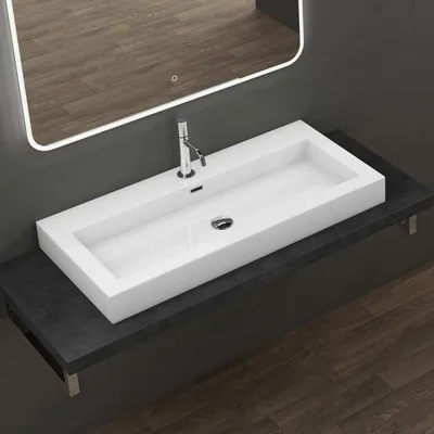 A modern bathroom sink with a chrome faucet is shown on a dark countertop, with a reflective mirror above.