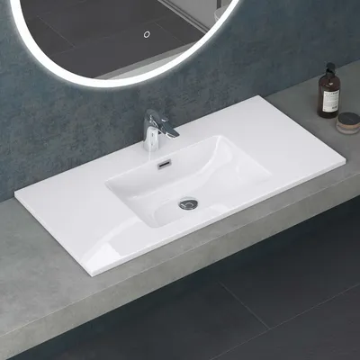 A modern bathroom sink with a faucet and a round illuminated mirror above it.