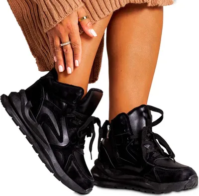 A person wearing black sneakers and a brown sweater.