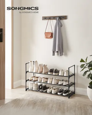 A shoe rack with shoes, a coat, and a handbag in an entryway.