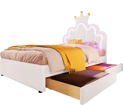 A white bed with a crown-shaped headboard and LED lighting, featuring two pull-out drawers. The bed is made up with bedding and a yellow throw blanket.