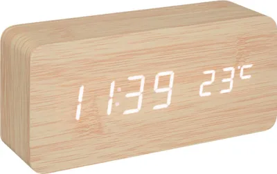 A digital alarm clock with a wood-grain finish displaying the time and temperature.