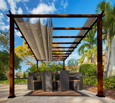 An outdoor dining area under a wooden pergola with a retractable canopy, featuring a table and chairs.