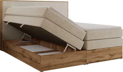 A boxspring bed with its storage compartment open, revealing the internal mechanism and storage space.