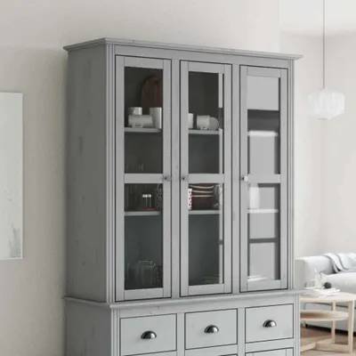 A gray wooden display cabinet with glass doors and drawers, shown in a room setting.