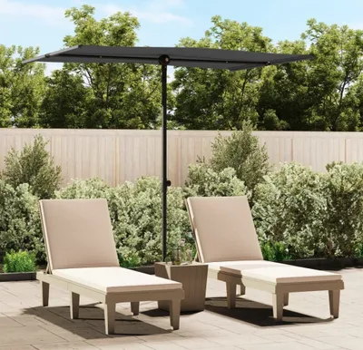 Two lounge chairs and a rectangular umbrella are set up on a patio with a wooden fence and lush greenery in the background.