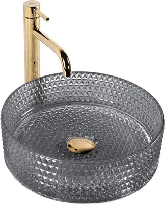 A close-up studio shot of a round glass vessel sink with a gold faucet.