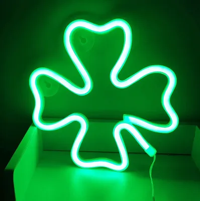 A green neon shamrock light is displayed on a shelf.