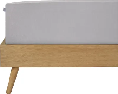 A close-up side view of a bed frame with a light gray fitted sheet.