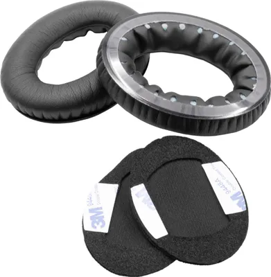 Two black headphone ear pads and two black foam inserts with adhesive strips are arranged on a white background.