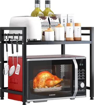 A black metal kitchen rack holding a microwave, a red appliance, and various kitchen items on the top shelf.