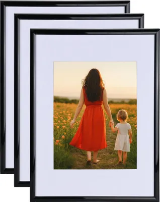 A stack of three black picture frames, with the front frame displaying a lifestyle image of a woman and child walking in a field.