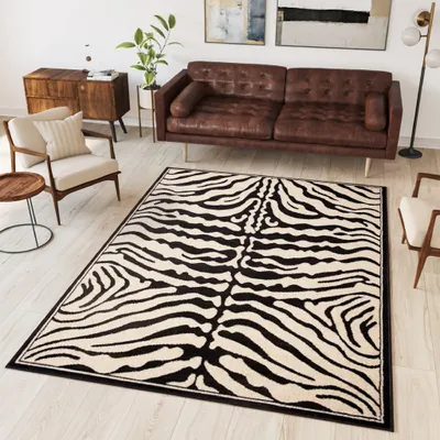 A living room scene with a brown leather sofa, a zebra-patterned rug, and wooden furniture.