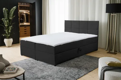 A black boxspring bed with a white mattress and headboard is shown in a modern bedroom setting.