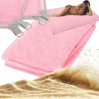 A woman is lying on a pink mat on the sand.