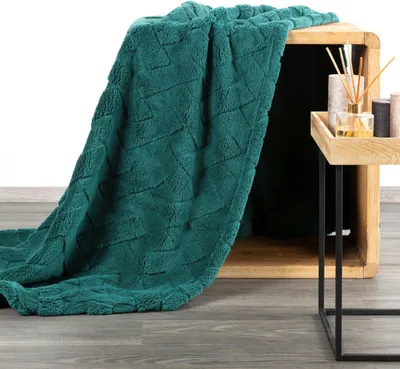 A dark green plush blanket is draped over a wooden crate, with a small side table holding decorative items next to it.