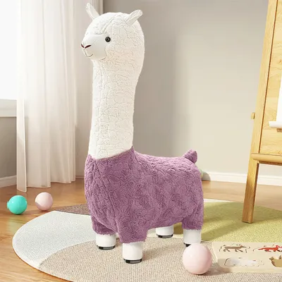 A plush alpaca stool sits on a rug in a room with a window and an easel in the background.