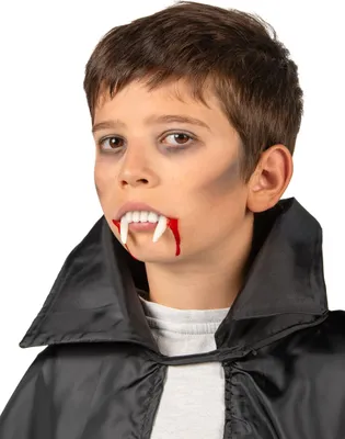 A young boy wearing a black cape and vampire fangs with fake blood.
