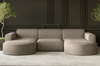 A modern U-shaped sofa in a neutral tone, set against a dark paneled wall with a minimalist aesthetic. Two potted plants flank the sofa, adding a touch of greenery.