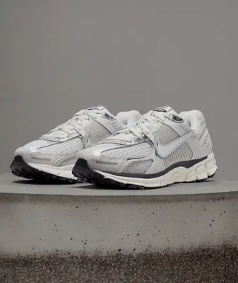 A pair of white Nike sneakers on a concrete surface.