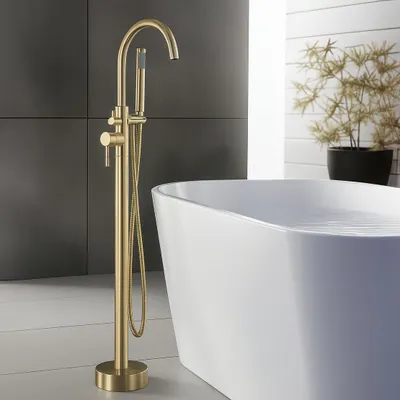 A modern bathroom with a freestanding bathtub and a gold floor-standing faucet.