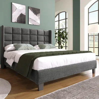 A bedroom scene with a bed, artwork, and a window.